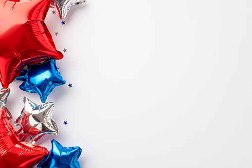 USA Independence Day decorations concept. Top view photo of balloons in national flag colors and star shaped confetti on isolated white background with blank space