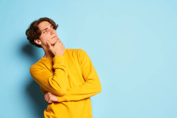 istock Portrait of young man with curly hair posing with thoughtful face isolated over blue background 1441397607