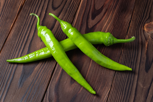 Fresh green peppers chili on wooden background.