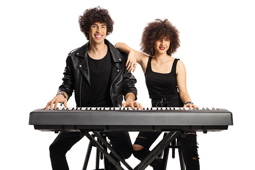 Young man and woman with curly hairs posing with a digital piano isolated on white background