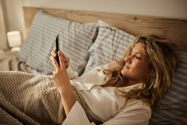 istock Young woman using mobile phone in a bed. 1441398133