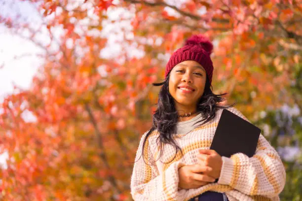 Photo of Asian girl in autumn with a tablet in her hand, technology concept