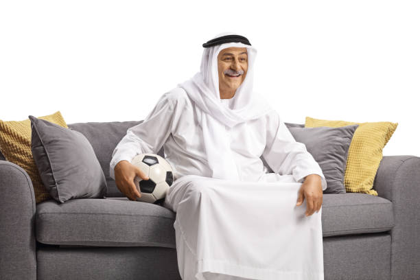 istock Mature arab man sitting on a sofa with a football 1441402838