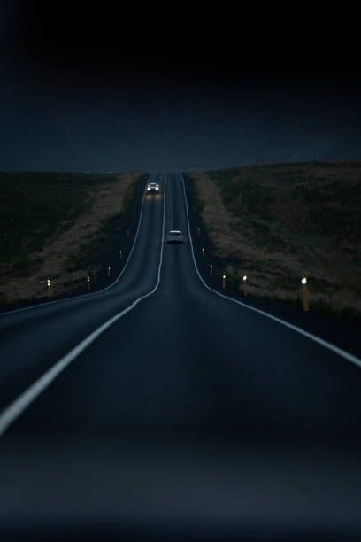 Open road on a remote location in Iceland, view from the inside of a car at night with cloudy sky