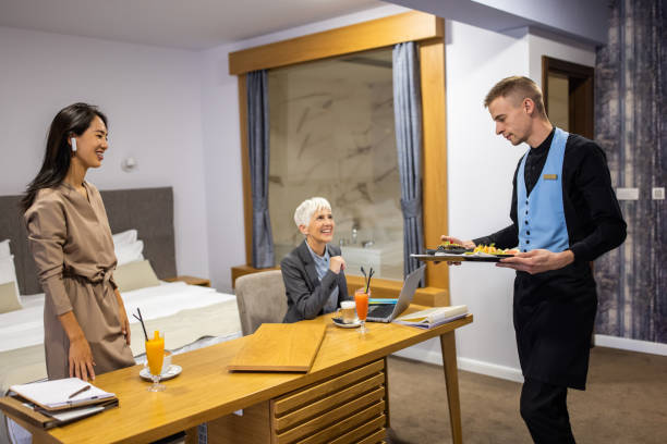 сотрудница отеля подает еду деловым женщинам в гостиничном номере - room service audio стоковые фото и изображения