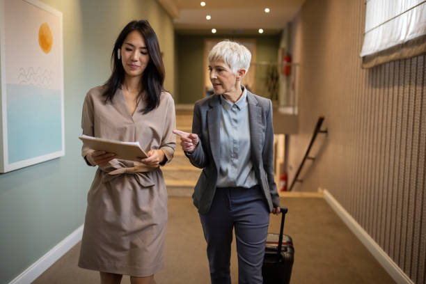 istock Businesswoman and her assistant checking schedule in hotel corridor 1441405892