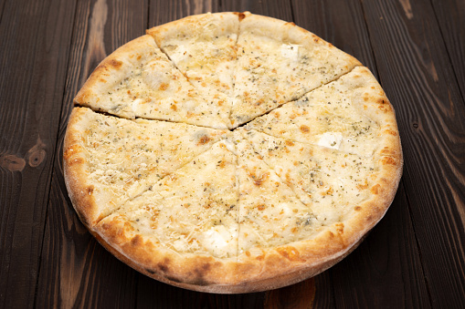 Pizza quattro formaggi slices on a wooden background. Cheese pizza. Copy spaace