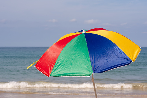 Multicolored beach umbrella against the sun on the background of the beach