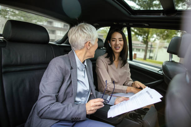istock Businesswoman reviewing documents with her assistant in car 1441409502