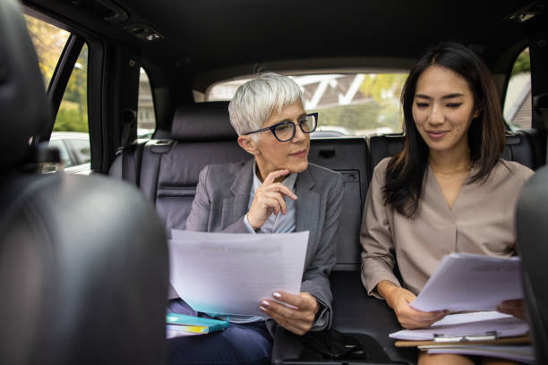 istock Female manager checking documents with business assistant in car 1441410366