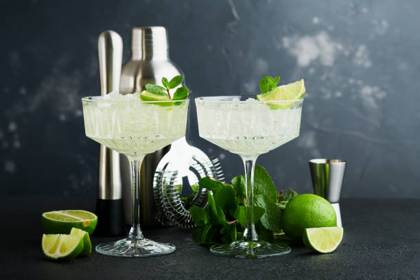 istock Margarita cocktail with lime, tequila, mint and ice on dark table with amazing backlight, copy space. Classic Margarita or Daiquiry Cocktail. Bar card or counter concept. Selective or soft focus. 1441411085