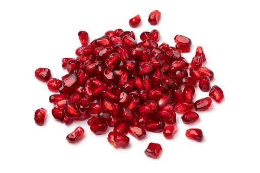 Heap of fresh red pomegranate seeds isolated on white background close up