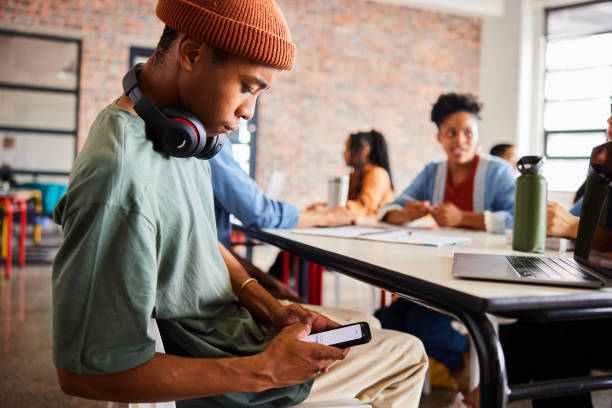 istock Young male student messaging on his phone during a class 1441414160