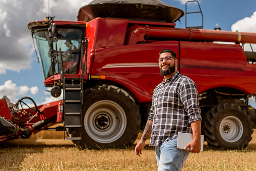Portrait of agronomist in front of agricultural machine
