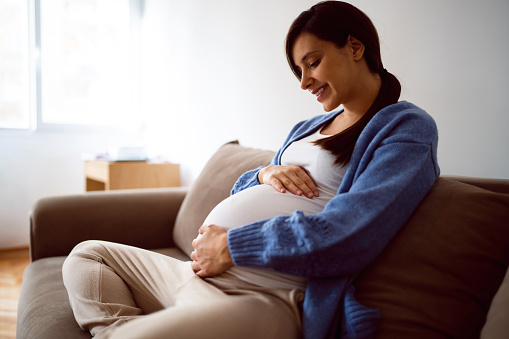 One woman, unrecognizable pregnant woman holding flowers bouquet.