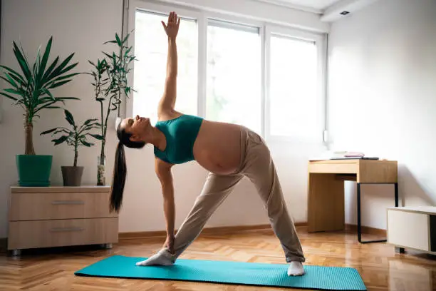 Pregnant woman practicing yoga at home.