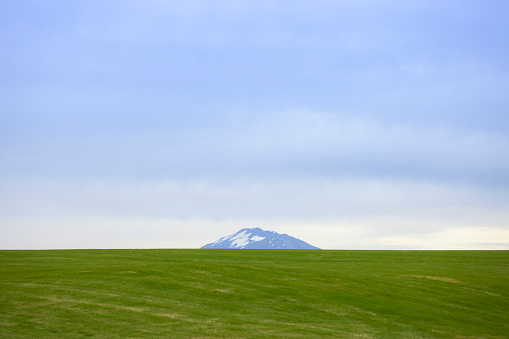 A wide green open field with the mountain in the distance on Iceland