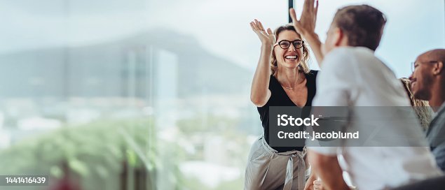 istock Businesswoman giving a high five to a colleague in meeting 1441416439