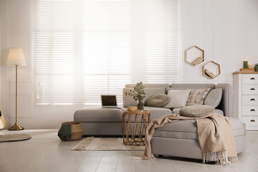 Sala de estar con cómodo sofá gris, otomana y elegantes elementos interiores cerca de la ventana photo