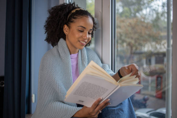 istock Happy woman reading book at home 1441416770