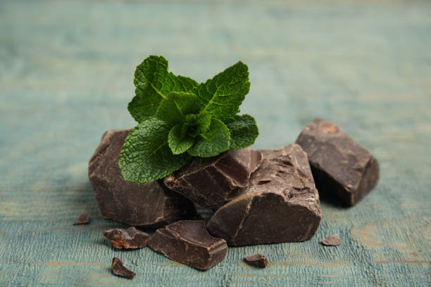 istock Tasty dark chocolate pieces with mint on blue wooden table 1441416925