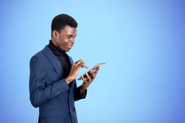 istock Handsome African American businessman is standing watching at tablet device 1441417851