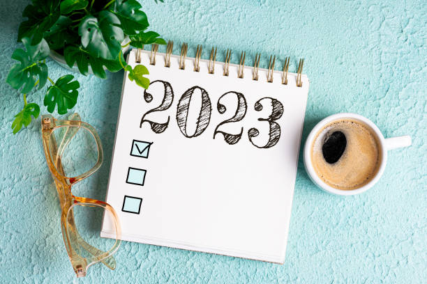 neujahrsziele 2023 auf dem schreibtisch. zielliste 2023 mit notizbuch, kaffeetasse, pflanze auf blauem tisch. vorsätze, plan, ziele, aktion, checkliste, ideenkonzept. vorlage für das neue jahr 2023 - determination new years eve list aspirations stock-fotos und bilder