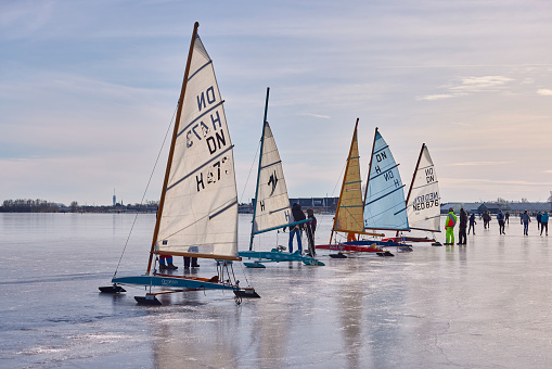 Ice sailing on the Braassemermeer near Roelofarendsveen in the municipality of Kaag en Braassem mede Veendermolen on a sunny day. It is mid-February 2021 in the Netherlands, people are skating and ice sailing on a large lake.