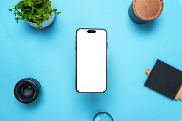 istock Phone mockup above a desk with objects around. Levitation above top view, flat lay composition. Isolated display for mockup, app user interface presentation 1441426448