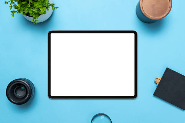 istock Tablet with isolated white display on blue table. Top view, flat lay composition. The plant, lens, box, magnifying glass and table beside 1441426485