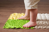 Baby toddler foots close-up on a medical orthopedic mat. Child legs with flat feet on a medical rug. Kid aged one year four months
