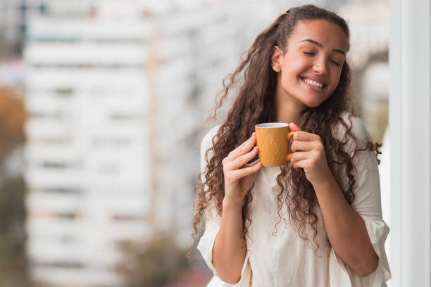 Woman with closed eyes enjoying a cup of coffee stock photo
