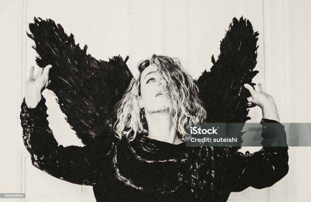 Black Angel. Portrait of young attractive blonde woman in black angel costume. Actor Stock Photo