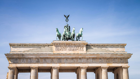 The top of the Brandenburg Gate in central Berlin, seen against a clear blue sky.