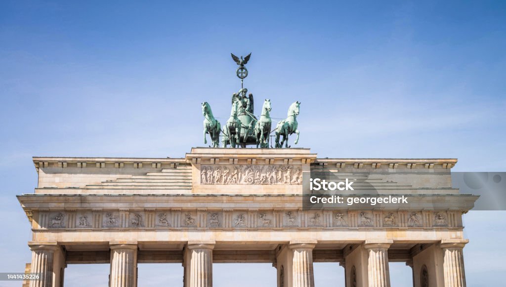 Horse and chariot statue on top of Brandenburg Gate The top of the Brandenburg Gate in central Berlin, seen against a clear blue sky. Brandenburg Gate Stock Photo