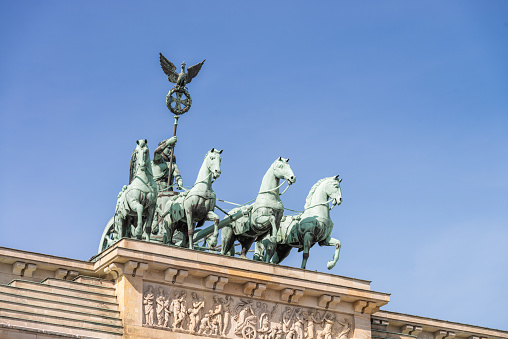 Close up image showing the four horses and chariot quadriga on top of the Brandenburg Gate in Berlin's city centre.