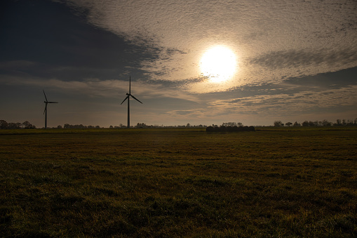 Wind turbine in a landscape with a field in the evening