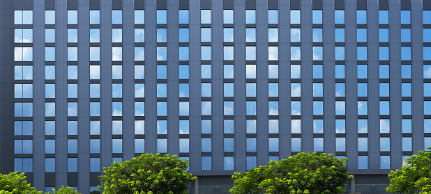 The pattern of the apartment, modern building, and blue sky reflex in the window glass.