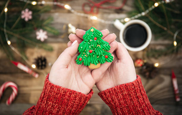 biscuit en forme d’arbre de noël gros plan dans les mains des femmes, vue de dessus. - cookie christmas shortbread christmas tree photos et images de collection