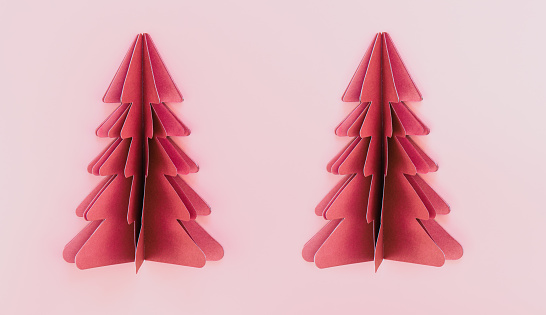Two pink paper origami christmas trees on pink background isolated, flat lay.