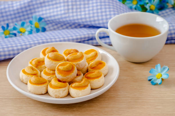 Cashew nut cookies or Singapore cookies on white plate and cup of tea Cashew nut cookies or Singapore cookies on white plate and cup of tea Rich Tea Biscuit stock pictures, royalty-free photos & images