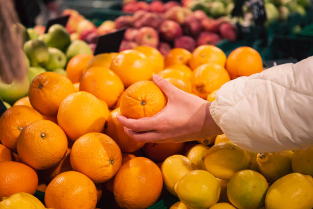 食料品店でオレンジを選ぶ女性の接写。 - close up women horizontal citrus fruit ストックフォトと画像