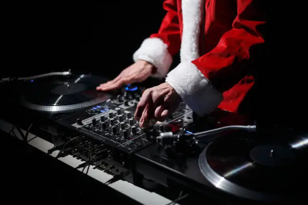 Disc jockey plays music set on New Year's Eve celebration while wearing traditional red Santa Claus costume on stage