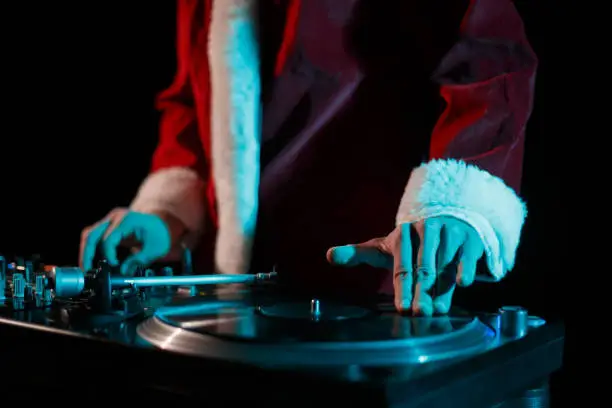 Disc jockey plays music set on New Year's Eve celebration while wearing traditional red Santa Claus costume on stage