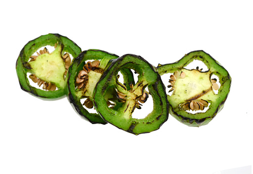 Grilled green jalapeno slices on white background