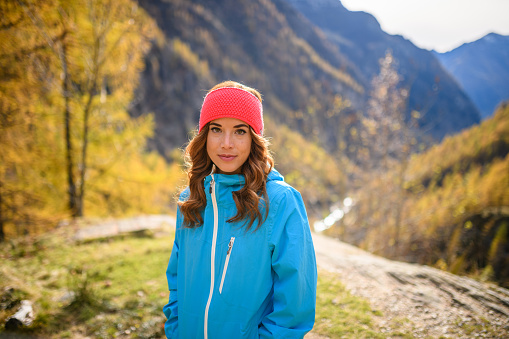 Beautiful young woman hiking in the Italian Alps in autumn