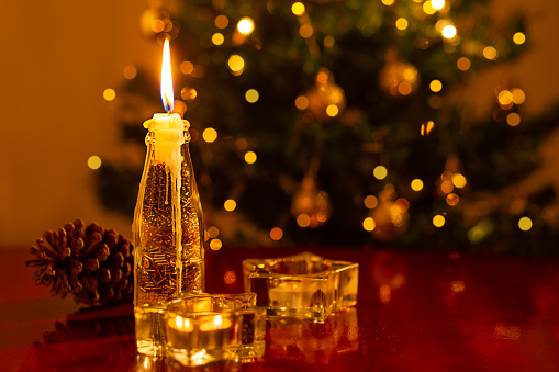 Goiânia, Goias, Brazil – November 14, 2022: Christmas decoration. A lit candle in the foreground, and a blurred Christmas tree in the background.