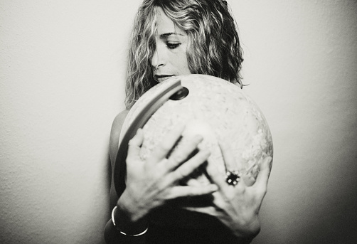 Portrait of a young attractive blonde woman holding a globe close to her.