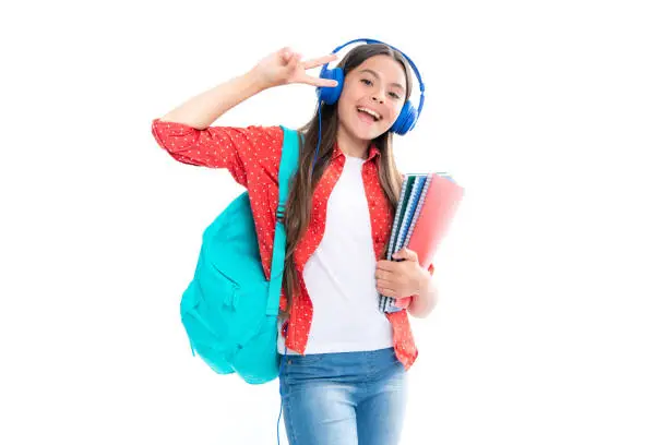 School girl, teenage student in headphones hold books on white isolated studio background. School and music education concept