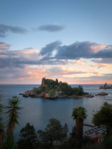 Sunset at Isola Bella, Sicily Isola Bella is a small island near Taormina, Sicily, southern Italy. Also known as The Pearl of the Ionian Sea. The island is surrounded by sea grottos and has a small and rather rocky beach which is a popular destination for sunbathers. isola bella taormina stock pictures, royalty-free photos & images